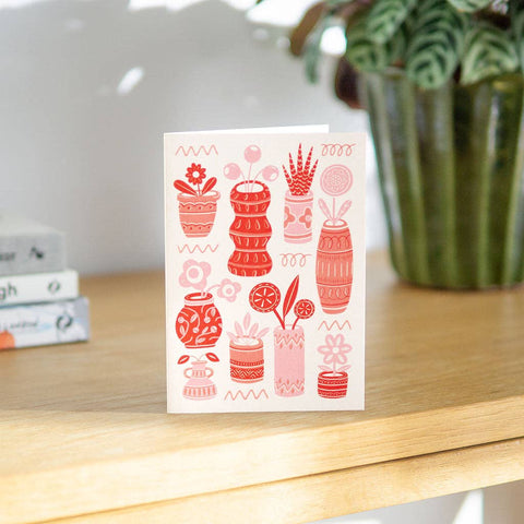 Tarjeta de felicitación con macetas y plantas rojas