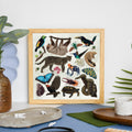 Framed artwork with illustrations of Amazon wildlife and animals on a table with plants and decor items.