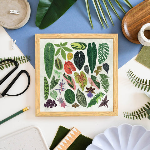 Framed artwork with leaf patterns on a table with craft supplies